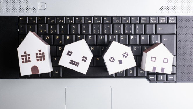 Mazas kartona mājiņas guļ uz klēpja datora klaviatūras