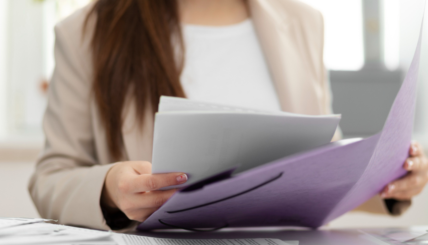 Sievietes rokas tur rokā dokumentu mapi