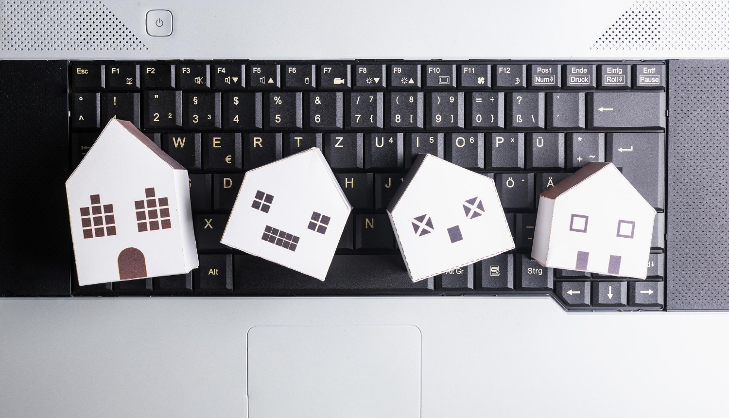 Mazas kartona mājiņas guļ uz klēpja datora klaviatūras