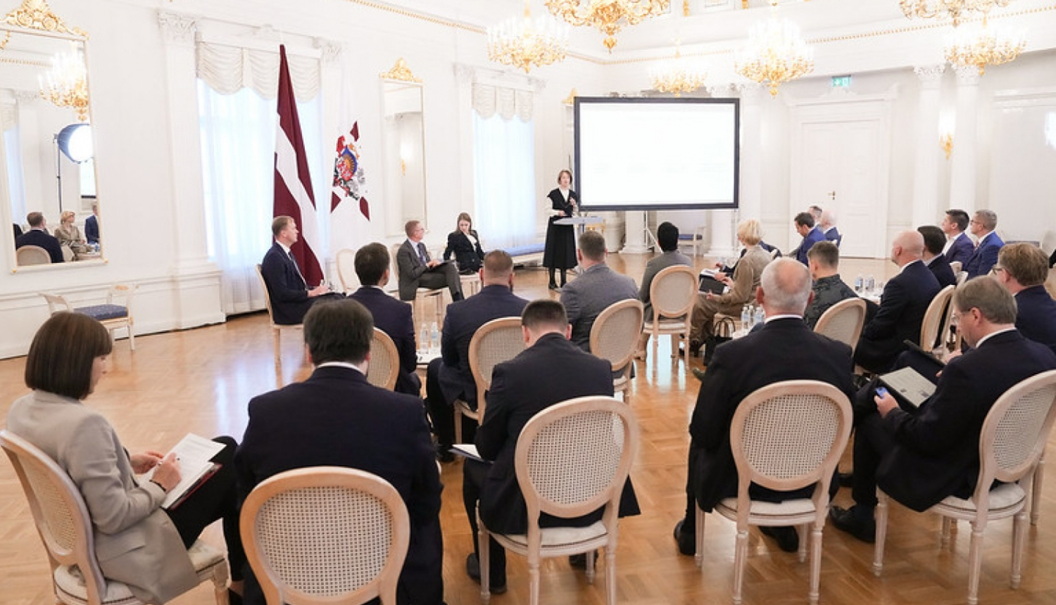 Sanāksmju zāle ar cilvēkiem, kuri klausās viedās administrācijas un reģionālās attīstības ministres uzrunu